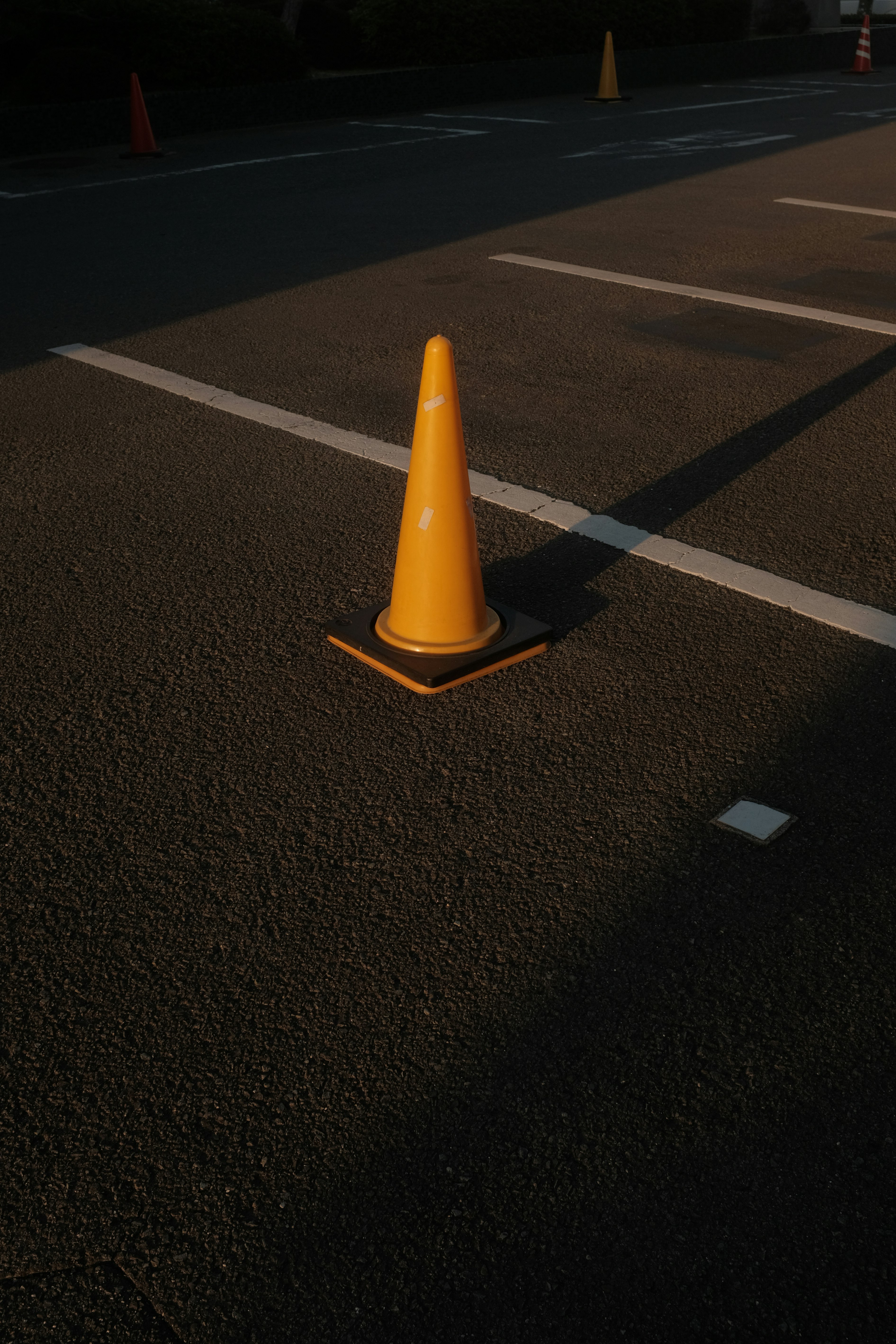 orange and white traffic cone on black asphalt road